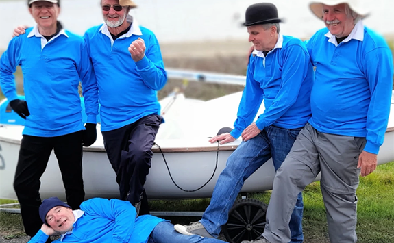 The group striking the same pose, but with a gap in the middle of the stood men to indicate the missing member of the group.